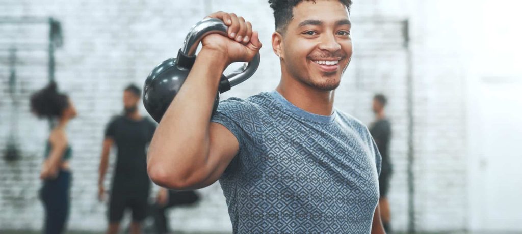 Portrait of a young man exercising with a kettlebell in a gym